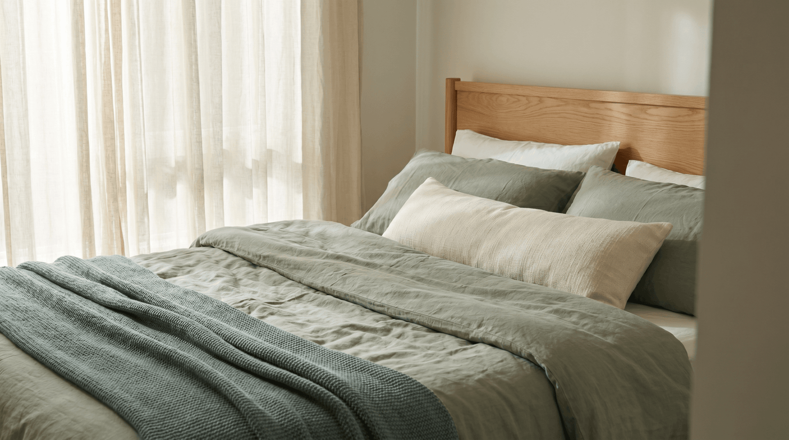 Bed setup arranged for back-sleeping support with thin head pillow and longer knee pillow in calm morning light